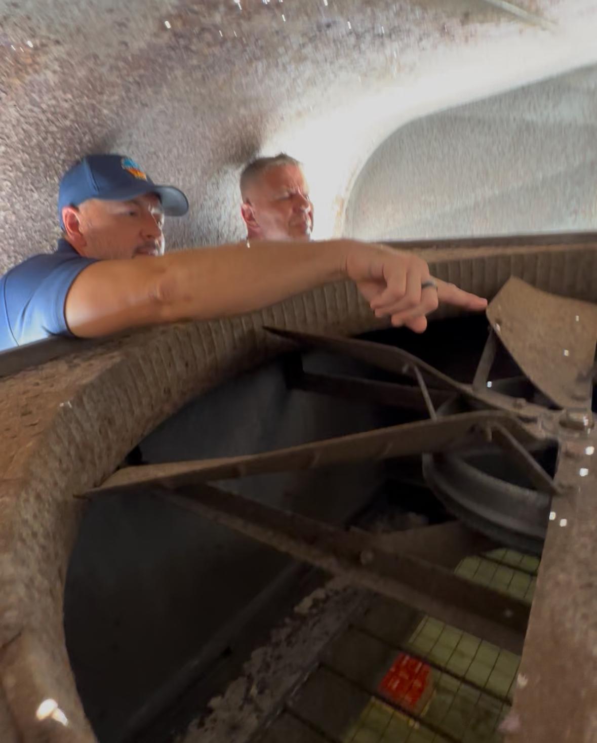 Air Force HVAC technician on rooftop catwalk with ocean view servicing commercial HVAC units